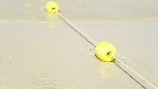 Yellow marker swim area buoys on sea. Yellow floating buoy over ocean.