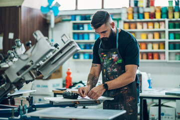 Male worker preparing screen printing film in a workshop