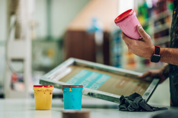 Male worker mixing colors for screen printing in a workshop