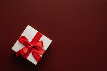 Presents with red bow on red background with heart confetti. Flat lay style. Valentine day concept. Saint VAaentines