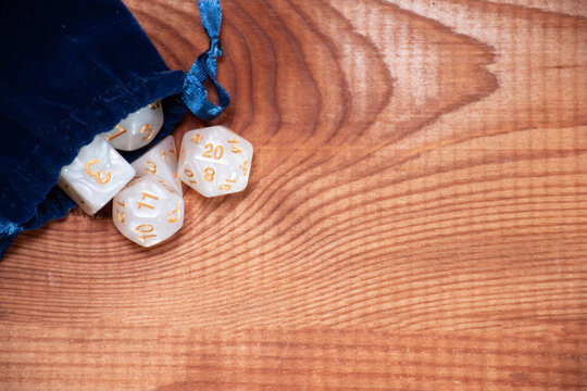 Set of role playing white dices in blue  storage bag on a gaming table made of wood: background for role-playing games with place for text, top view