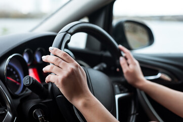 Fototapeta na wymiar Women's hands on the steering wheel, inside the car.