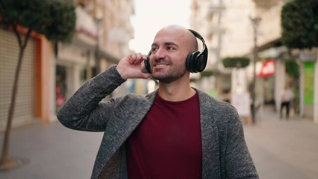 Young bald man smiling confident listening to music at street