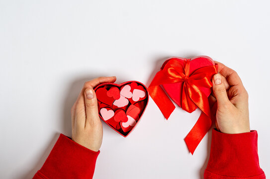 Red gift box with different hearts in female hands for Valentine's Day on a white background