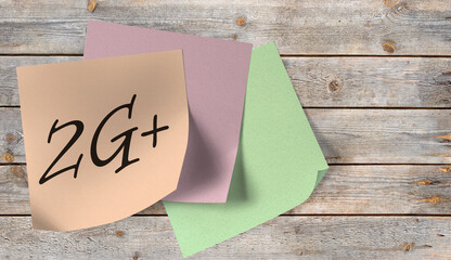 Zettel mit der Aufschrift 2G+  an einer Holzwand