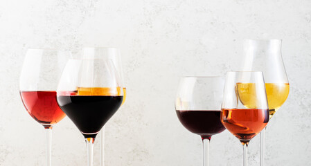 Red, rose and white wine glasses set on gray table background. Wine tasting. Hard light and harsh shadows