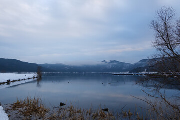 A view of an extremely cold lake covered with snow in the middle of winter.