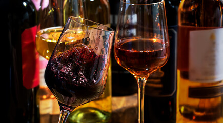 Red, white and rose wine in glasses on wooden background and collection of wine bottles, copy space