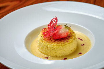Cheesecake with sauce in a white plate on a wooden background