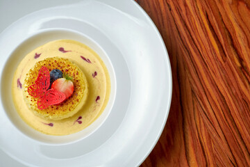 Cheesecake with sauce in a white plate on a wooden background