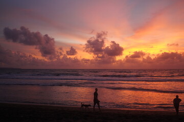 silhouette of a man on the ocean beach at sunset, winter in Bali, red-orange clouds