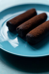 Chocolate cake on blue plate on blue table background. Delicious bakery food delivery. Copy space. Vertical shot. Cafe concept.