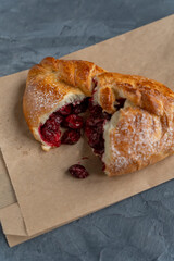 Bakery pastries on grey background. Freshly cooked bakery with cherry for delivery or take away. Home cooked bakery for morning breakfast. Copy space. Vertical shot. Selective focus