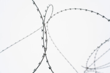 Barbed wire on white cloudy sky background
