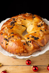 Aerial view of round chocolate brioche on rustic wooden table, black background, vertical, with copy space