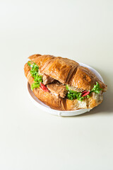 Croissant with terriyaki chicken on a white plate