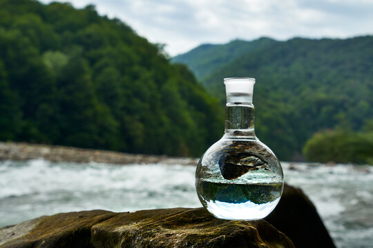 Bottle of drinking water on the shore of a mountain river.