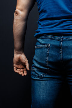 slender guy with an elastic ass. a man in jeans on a black background, rear view. space for text.concept: men's health, skin disease - vitiligo. spots on the skin