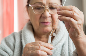 Senior woman taking Rapid Antigen test for self-diagnostic SARS-CoV-2, Covid-19, Coronavirus at...