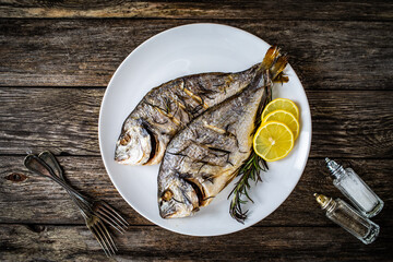 Roast sea bream with rosemary and lemon on wooden table
