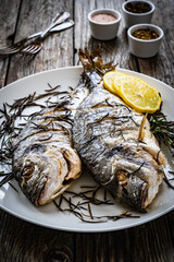 Roast sea bream with rosemary and lemon on wooden table
