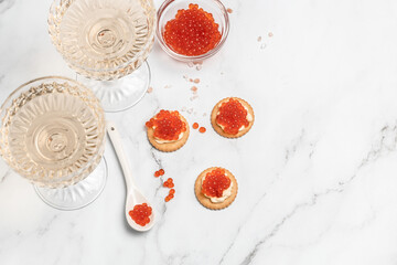 Glasses of champagne and caviar on gray background. Delicious red caviar appetizer, banner, menu,...