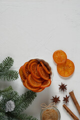 candied oranges in the bowl and spruce branch and spices and Christmas decor on white table. Space for text