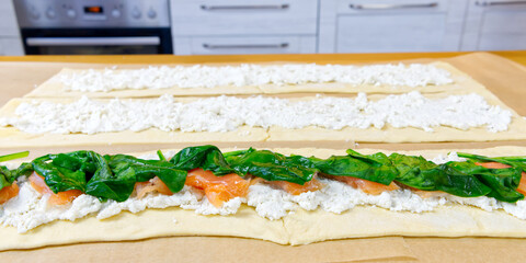 the cook puts spinach and trout on the dough. Savory Christmas pie in the shape of a wreath cooking process. close up