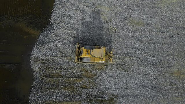 Top down view of powerful bulldozer working flattening base with granite rubble for building in swamp area. Business concept construction and heavy industry