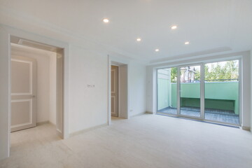A spacious, bright hall on the ground floor with a large window and beige doors.