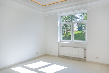 A bright unfurnished room with a window and a high ceiling.