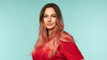 Obraz premium Portrait of a beautiful young woman in a red t-shirt on a blue background in the studio