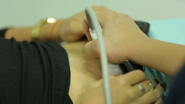 Doctor do ultrasound devices monitor diagnostic to a woman patient. Sonography. The patient's belly. Close up