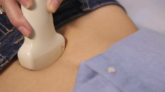 Doctor do ultrasound devices monitor diagnostic to a woman patient. Sonography. The patient's belly. Close up