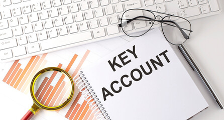KEY ACCOUNT text written on a notebook with keyboard, chart,and glasses