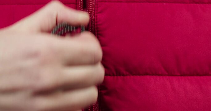 Hand unzipping red clothes close-up. Tailoring and sewing concept. Handmade things, dressmaking, macro shooting of textile sample.