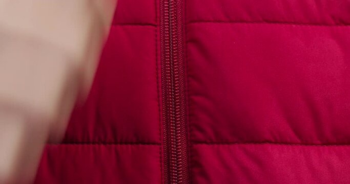 Hand zipping up red clothes close-up. Tailoring and sewing concept. Handmade things, dressmaking, macro shooting of textile sample.