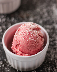 Strawberry ice cream ball with coconut in a bowl, on a white background. home made ice cream. healthy. clean eating. vegan. plant based.