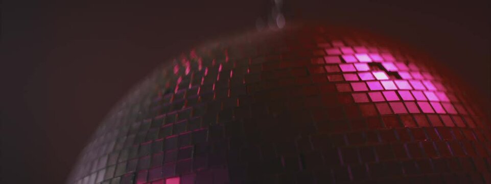 Disco ball with silver mirror surface. Pink light. Night party in club, music and entertainment concept.