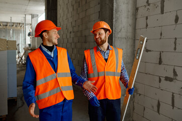 Two builders in uniform walking and talking about construction