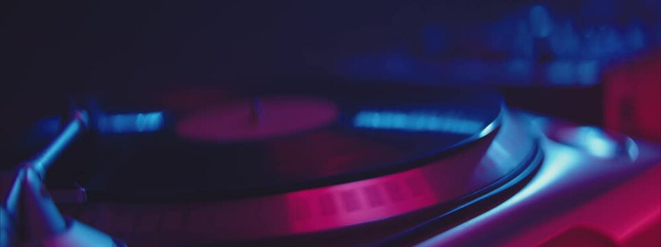 Rotating vinyl record on turntable in dim environment. Night party in club, music and entertainment concept.