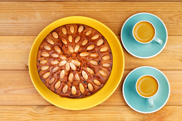 Homemade cake with almonds and two cups of coffee espresso on a wooden table. Top view.