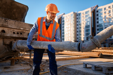 Male construction worker connecting pipe at site