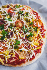 vegan homemade pizza with cherry tomatoes olives and fresh herbs topped with dairy-free cheese, healthy plant-based food
