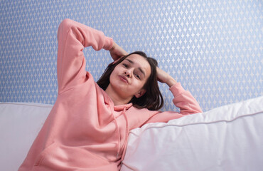 Naklejka premium a girl in a pink sweater on a white sofa is resting and touching her head with her hands 