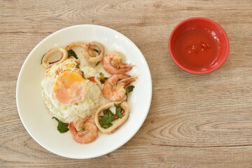 spicy stir fried shrimp and squid basil leaf topping egg eat couple with rice on plate