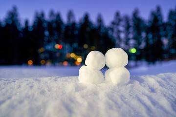 ゲレンデのナイター照明を背景に寄り添う２つのカップル雪だるま