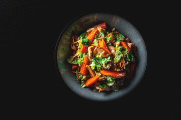 Chicken, carrot, lettice salad in plate on black background