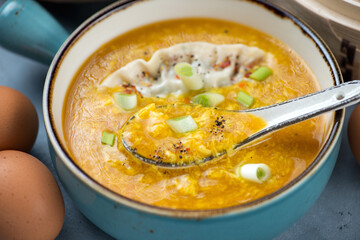Close-up of chinese traditional egg-drop soup served with steamed dumpling in a turquoise bowl, selective focus