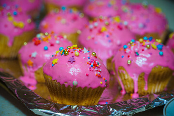 Freshly baked vanilla muffins are garnished with sweet icing and topping.